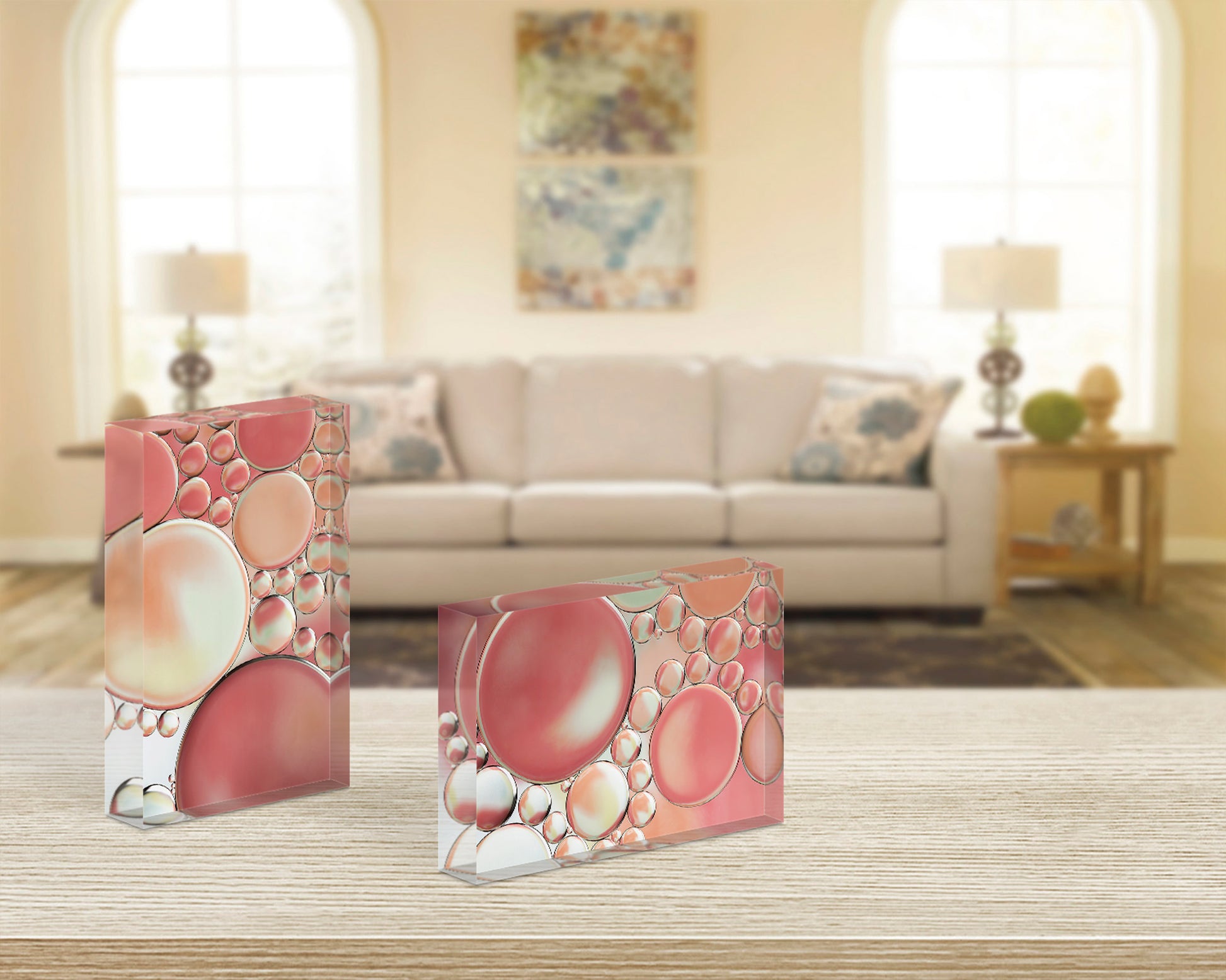 Pair of acrylic blocks - Blossoms 1 and 2 abstract bubble art in peach, pink, and warm beige - styled on light wood table in modern living room.