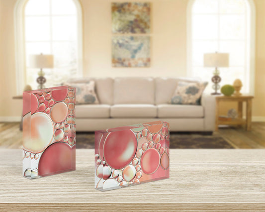 Pair of acrylic blocks - Blossoms 1 and 2 abstract bubble art in peach, pink, and warm beige - styled on light wood table in modern living room.