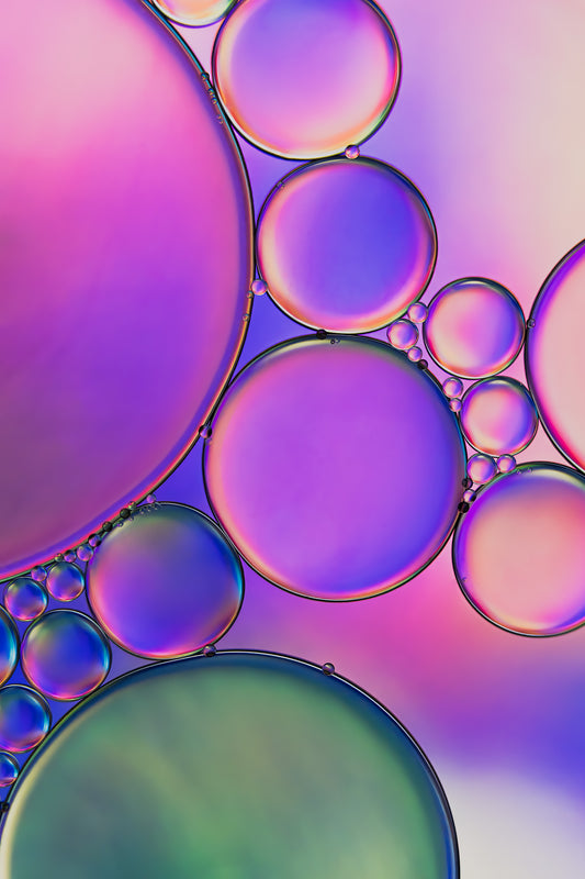 "Twilight 2" is a macro photograph presenting an abstract design created by the interaction of oil and water. The image predominantly features shades of purple, pink, blue, and green, blending into each other to create a dreamlike, fluid scene. The photograph has a peaceful, almost otherworldly quality, and the contrasting textures of oil and water add depth and interest to the composition.