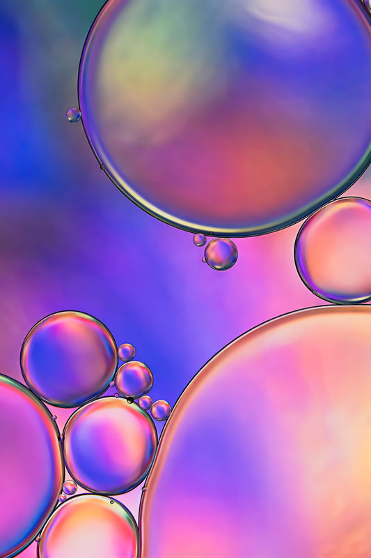 "Twilight 3" is a macro photograph presenting an abstract design created by the interaction of oil and water. The image predominantly features shades of purple, pink, blue, and green, blending into each other to create a dreamlike, fluid scene. The photograph has a peaceful, almost otherworldly quality, and the contrasting textures of oil and water add depth and interest to the composition.